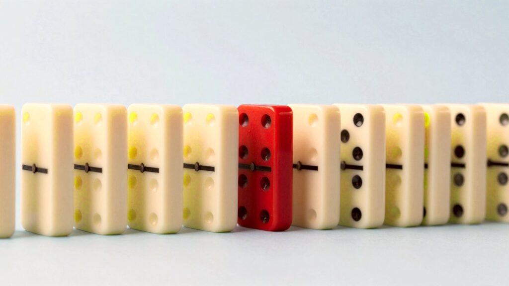 A row of identical white domino tiles with one small red tile hidden in the middle.
