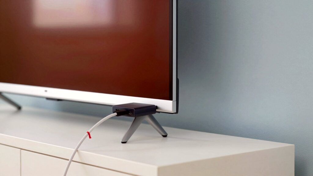 Primer plano de un pequeño stick de streaming negro conectado a un puerto HDMI en la parte trasera de una tele.